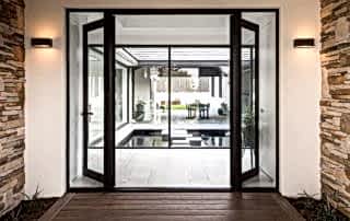Black French doors opening out into area with water feature of a Perth home