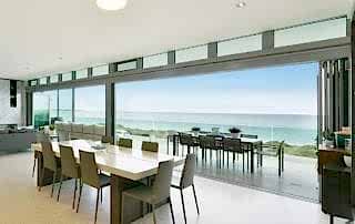 Bifold doors of a home in Perth that opens from the dining to outdoor area with views of the sea
